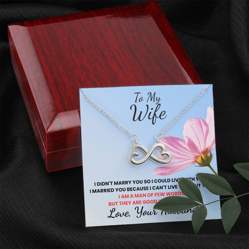 Necklace with infinity symbol on a card for 'To My Wife' with a pink flower and wooden box in the background.
