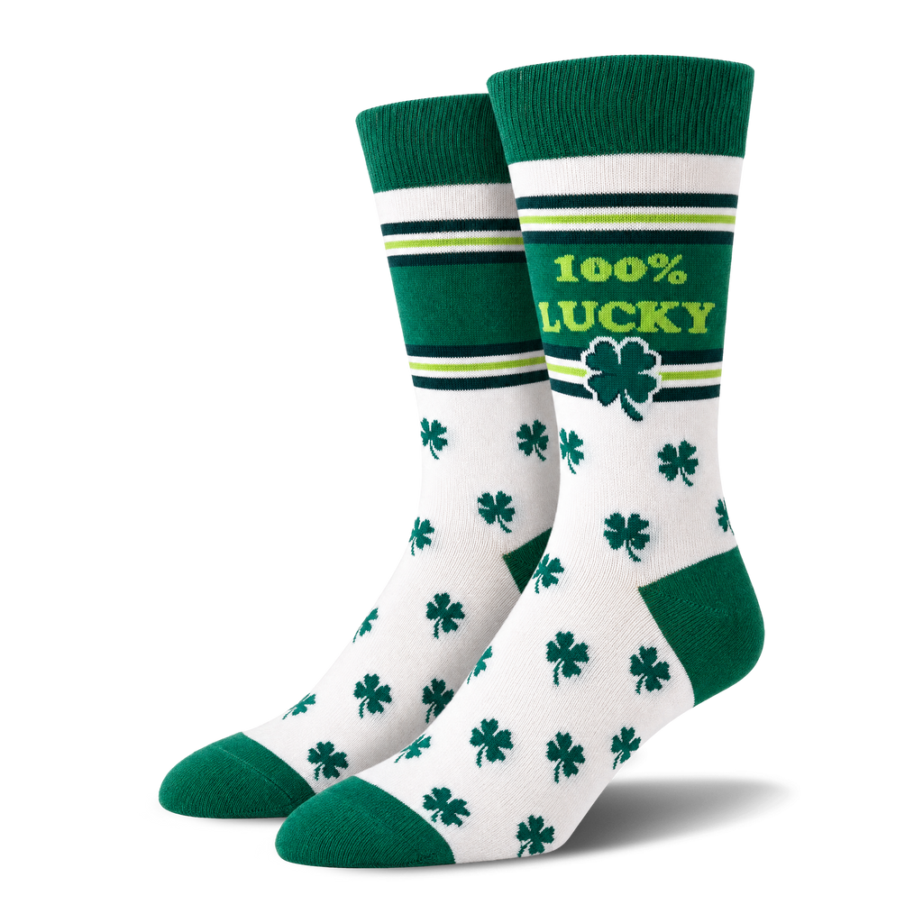 A pair of white crew socks with green toes, heels, and cuffs, decorated with green shamrocks and a green band that reads '100% LUCKY' with a shamrock, set against a plain white background.