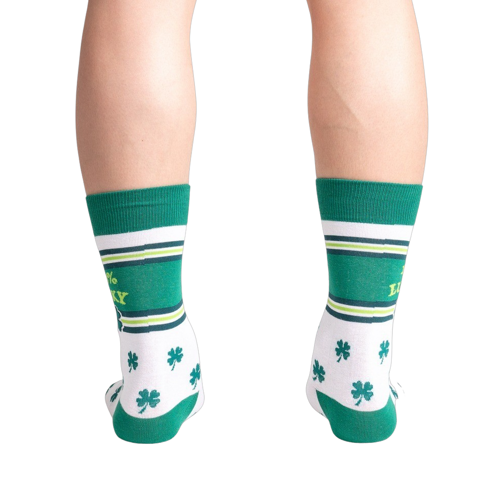 Green and white socks with shamrock pattern worn by a person on a white background