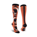Pair of knee-high socks with black cat and skull design on an orange background