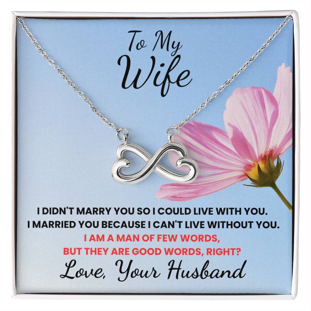 Silver necklace with heart and infinity symbol on a card with text and a pink flower.