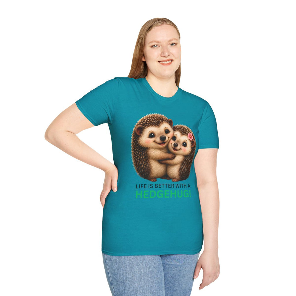 A woman modeling a teal short-sleeve t-shirt with a graphic of two hugging hedgehogs and the text 'LIFE IS BETTER WITH A HEDGEHUG.' on the front, paired with light blue jeans against a plain white background.