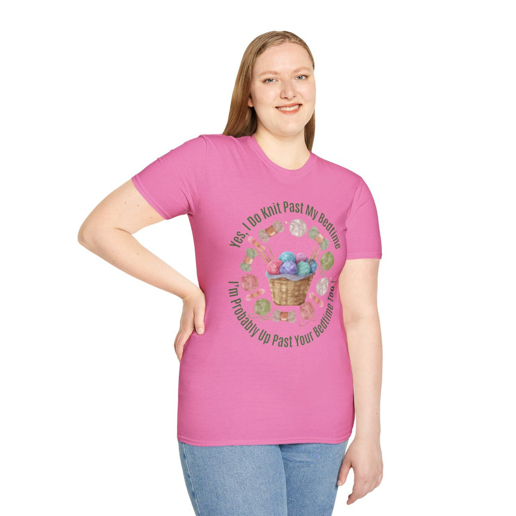 A woman modeling a pink short-sleeve graphic t-shirt with a circular design featuring knitting needles, yarn balls, and the text 'Yes I Do Knit Past My Bedtime. I'll Probably Up Past Your Bedtime' in a clean white studio background.